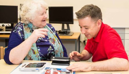Our very own Jamie Bruce with one of our service users showing them to use a magnifier
