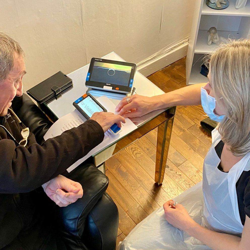 Visibility Scotland staff member, Jeni, demonstrating different digital magnifiers to a service user during a home visit