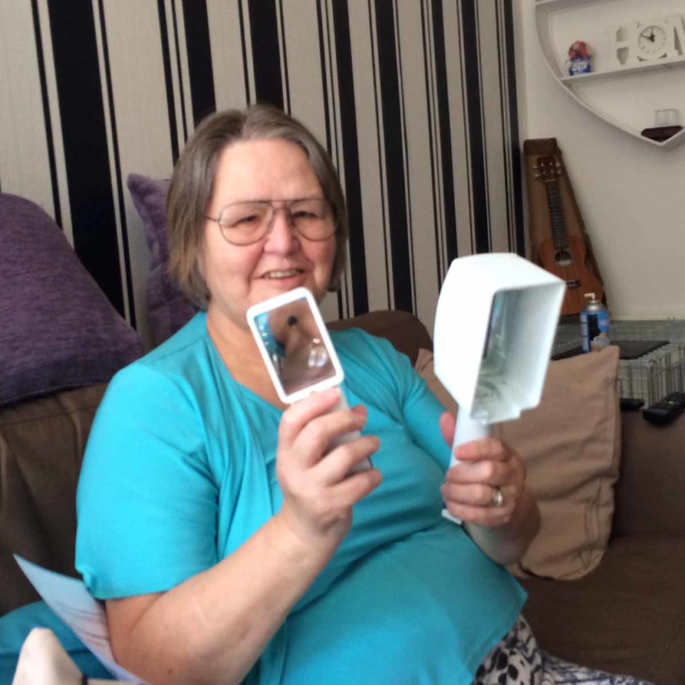 A smiling lady using a magnifier