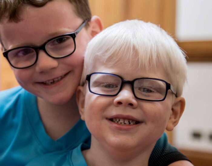 Two young children wearing glasses and smiling