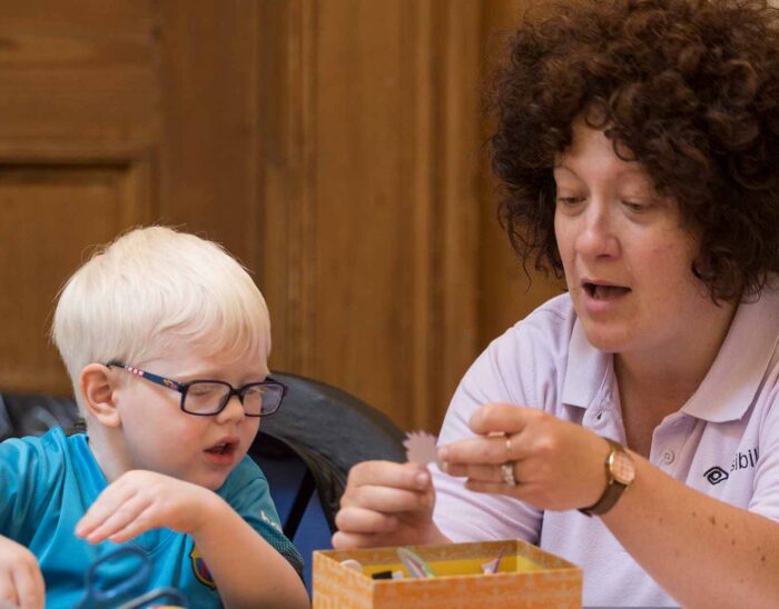 Visiblity Scotland worker and young child looking at art materials
