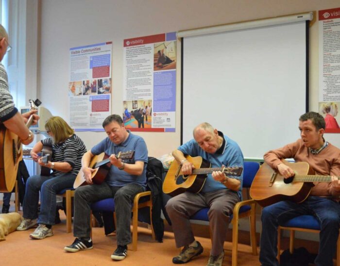 Four guitar players playing and singing at our group in Glasgow