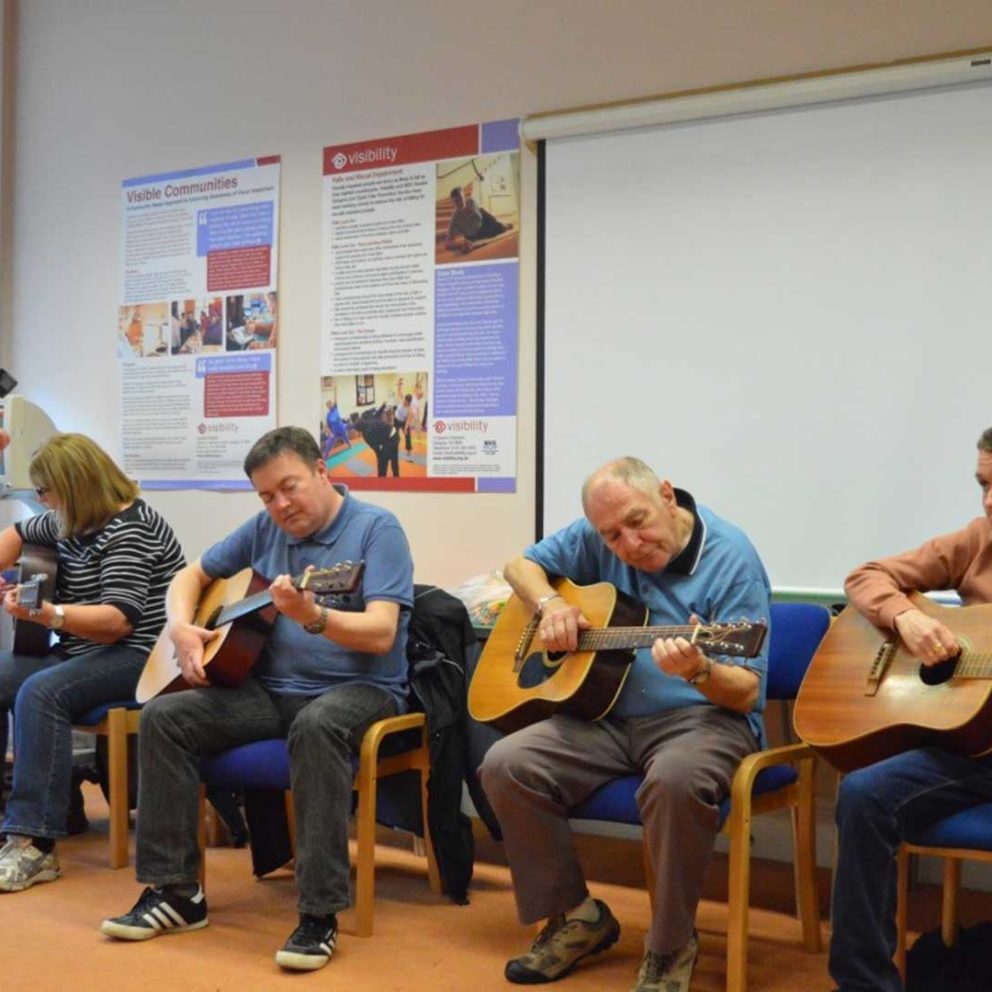 Four guitar players playing and singing at our group in Glasgow