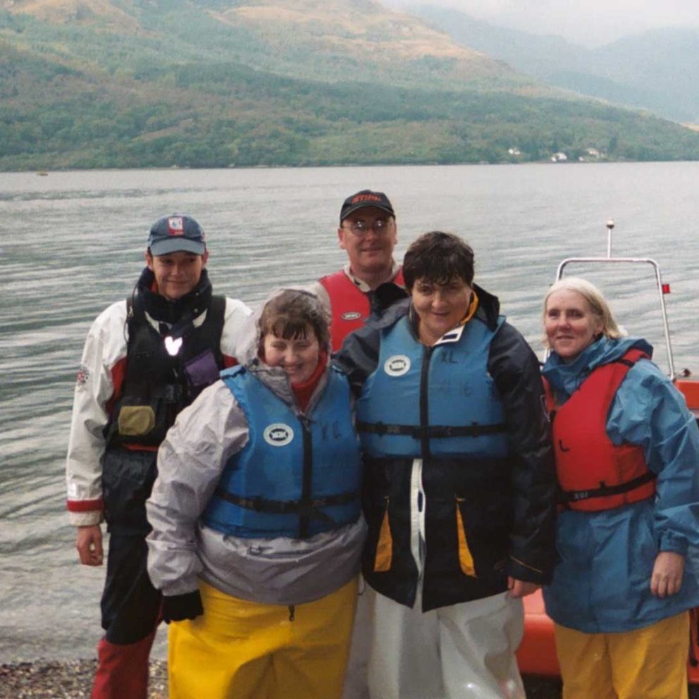 Group wearing life jackets on loch shore