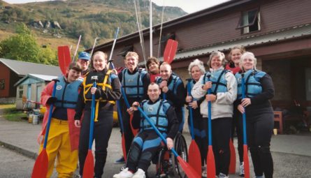 Smiling group wearing life jackets and holding paddles