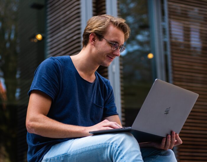 university student sitting outside working on a laptop
