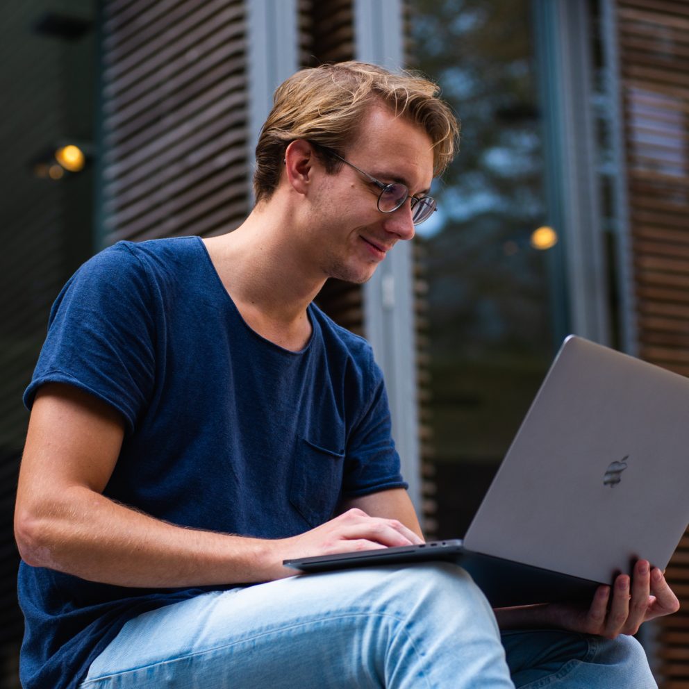 university student sitting outside working on a laptop