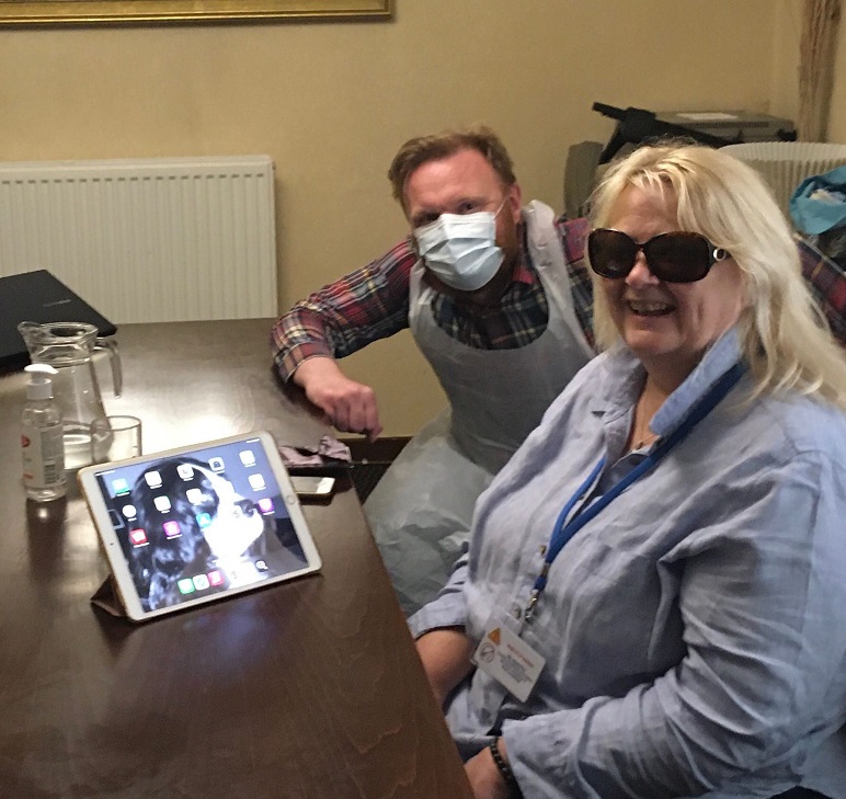 Visibility Staff member, Craig, and service user, Nicola, sitting at a table with an iPad and iPhone on it.