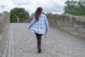 Zee using her white cane to cross a cobbled bridge.