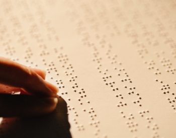 Hand moving over a text in braille.