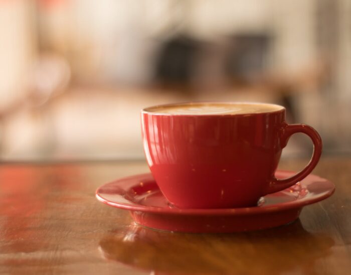 A red tea cup and saucer sitting on a table.