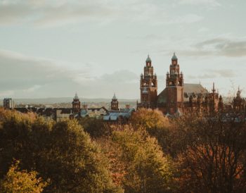 The view of Kelvingrove Art Gallery from Kelvingrove Park. The gallery is a large, ornated, red sandstone building.