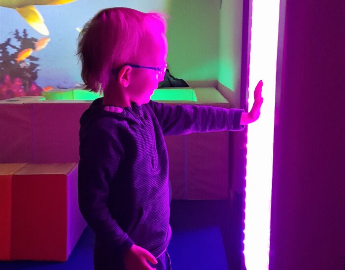 A young boy touches an illuminated sensory wall.