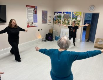 Kirsteen from New Rhythms for Glasgow leading a ‘Recovery Rhythms’ taster session. Two participants are taking part.