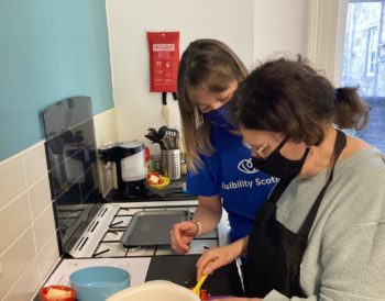 Visibility Scotland’s occupational therapist, Heather, supporting a service user during a practical cookery session in our accessible kitchen.