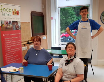 Three service users sitting at a table at our wellbeing café, The Haven. The café chef, Xander, is standing behind them.