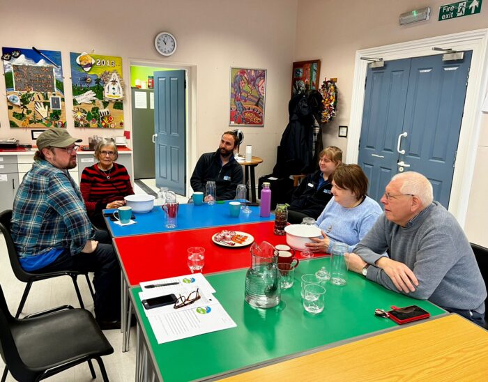 A group sitting round a table, enjoying refreshments and a chat.