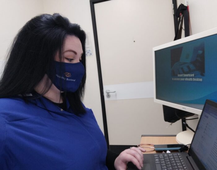 Seannie, Patient Support Worker at St. John's, sitting at her desk in the eye department working on her laptop.