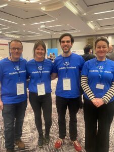 Four members of the Visibility Scotland team pose in blue Visibility Scotland t-shirts
