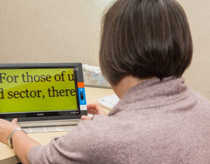 A woman using a digital magnifier to read a newspaper.