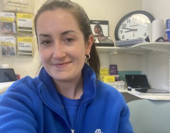 Miriam sits in our patient support room at Gartnavel General Hospital. Miriam is wearing a blue Visibility Scotland fleece and t-shirt and is smiling.