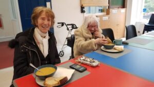 two of our charged up cafe attendees smile while enjoying some soup and bread at the cafe.