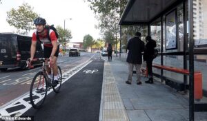 A cyclist riding parallel in front of a bus stop.