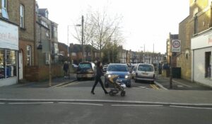 A person with a buggy walking across a continuous pavement
