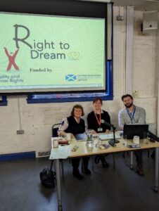 Photo of Adam, our Training and Development Worker, sitting in front of the Right to Dream presentation which is being delivered to Sense Scotland staff. Next to Adam are his two colleagues from the project.