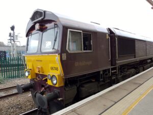 The engine of a dark purple and yellow GB rail freight train