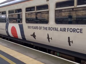 Side of a passenger train car with silhouettes of old aircrafts and the words "100 years of the Royal Air Force" printed on it