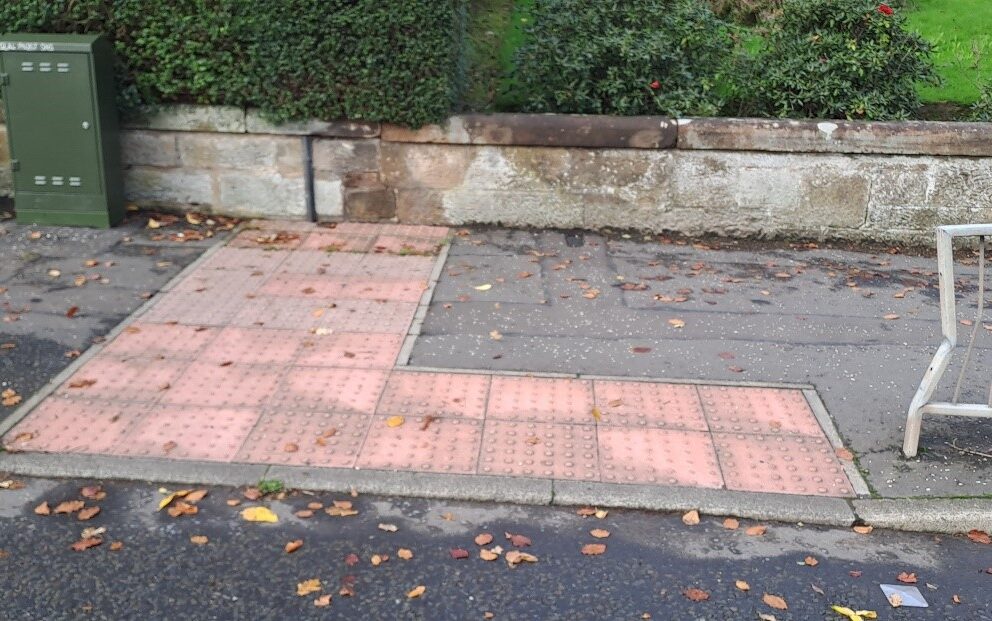 red blister paving in an L-shape next to a controlled crossing