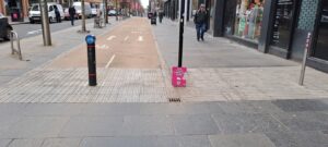 Picture of a city centre street with cycleway paving between the road and the main pedestrian walking area