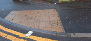 Tan/sand blister paving on a pavement next to a road