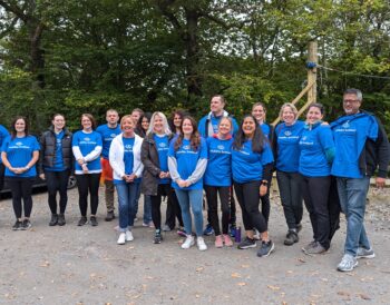 A group of people stand together smiling and wearing blue branded Visibility Scotland tops