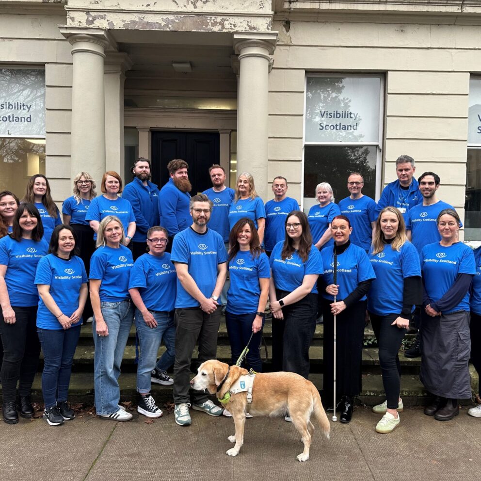 Visibility Scotland staff and Gina the guide dog stand outside the main Visibility Scotland office building
