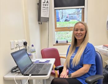 A person sits at a desk smiling at the camera.