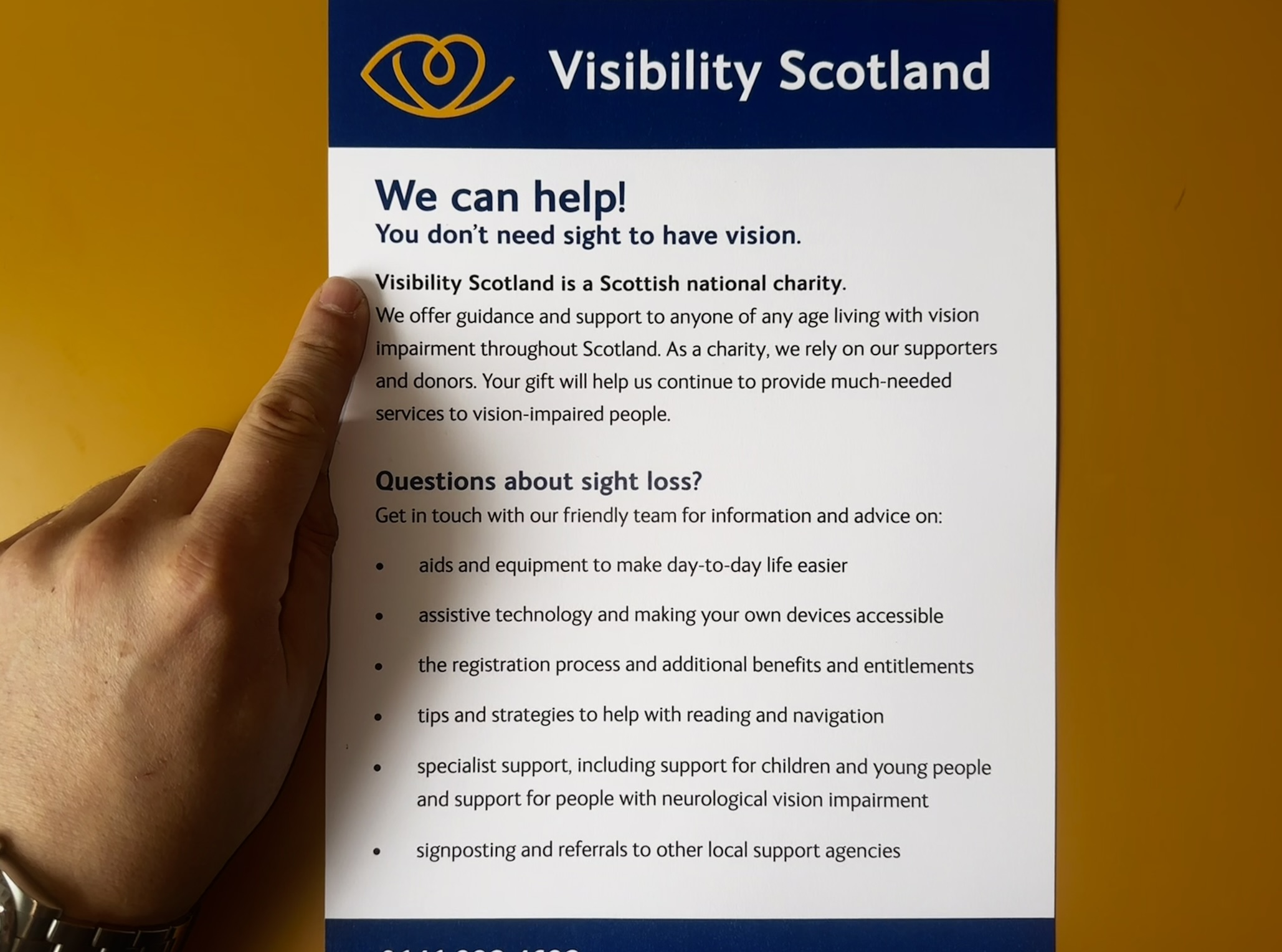 A finger placed as a visual anchor on the lefthand side of a pamphlet