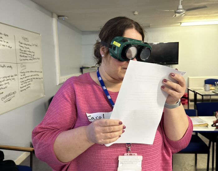 A person attempts to read a document while wearing simulation goggles