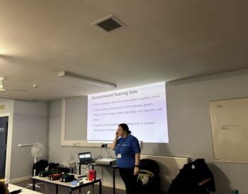 A oerson stands in a room presenting a slide on sensorineural hearing loss