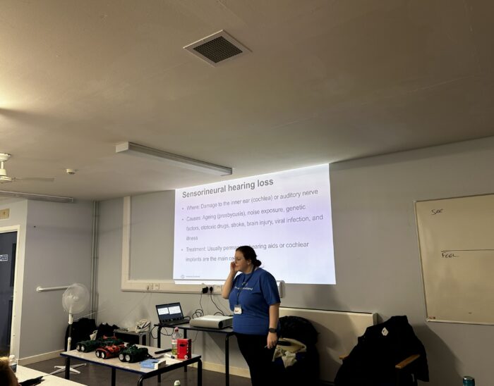 A oerson stands in a room presenting a slide on sensorineural hearing loss