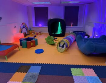 Play and sensory equipment laid out in a large room.