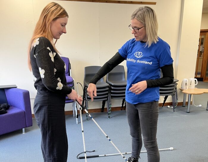An instructor demonstrates proper technique when using a guide cane with a student.