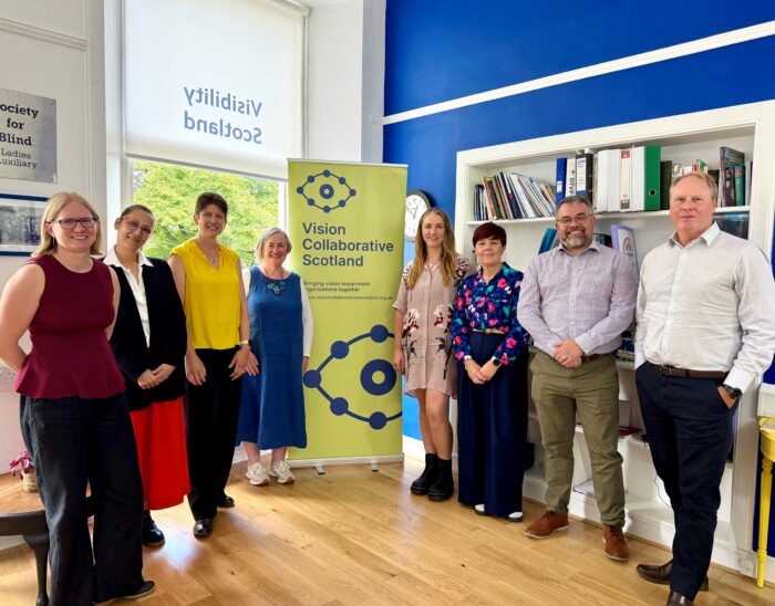 Vision Collaborative Scotland leaders stand with MSP Allison Thewliss next to a Vision Collaborative Scotland banner