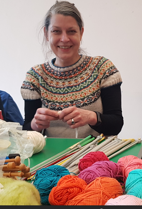 A person smiling while knitting